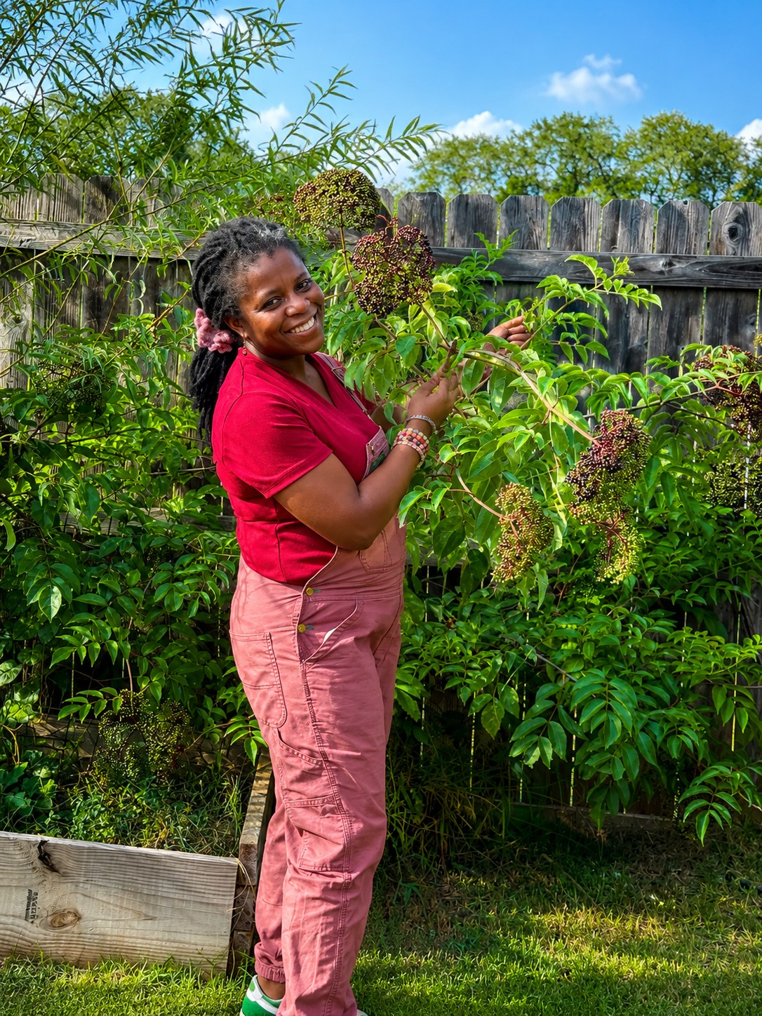 Veravyn's founder pausing to smell a ripening elderberry cluster in the garden